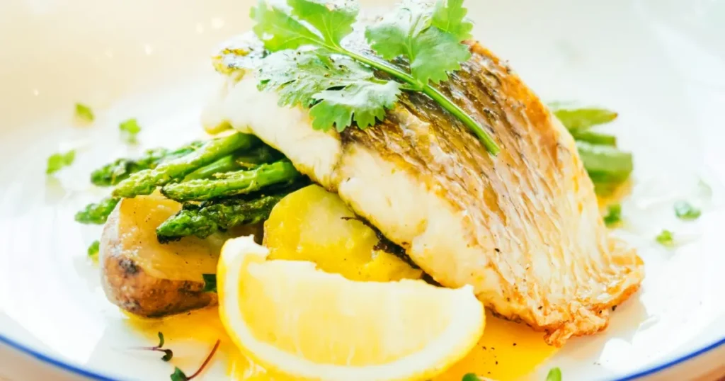 Barramundi fillet served on a bed of asparagus and potatoes